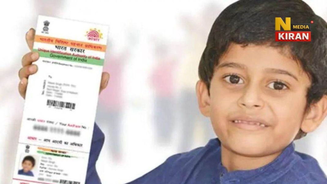 a boy is holding his aadhar card in blue shirt and smiling